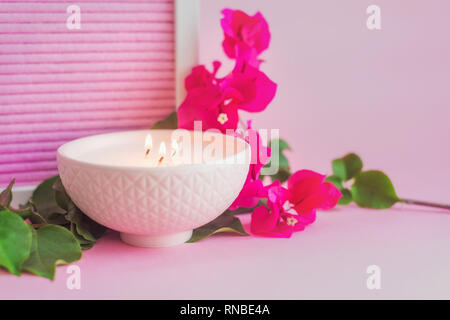 Rosa vaso in ceramica con candela e fiore rosa su sfondo rosa Foto Stock
