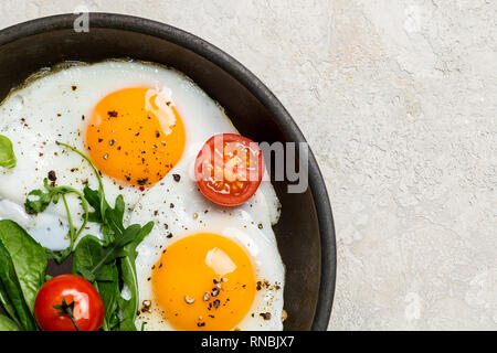 Spazio libero con uova fritte con le erbe aromatiche e i pomodori ciliegia sulla teglia. Bordo sinistro angolo, spazio libero Foto Stock