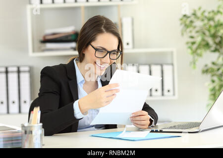 Felice lavoratore di ufficio la lettura di una lettera su carta in un desktop Foto Stock