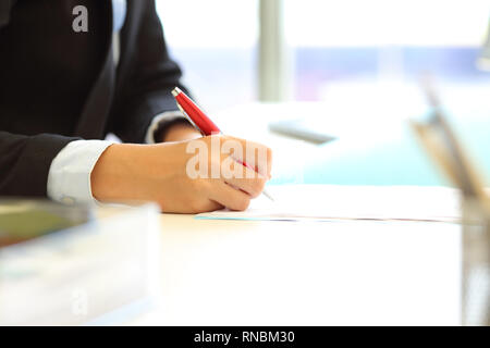 Close up di un lavoratore di ufficio mano firma contratto o scrivere sul documento su un computer desktop Foto Stock