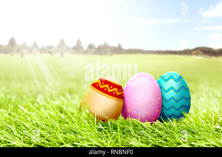 Colorate le uova di pasqua sul campo di erba con alberi e cielo blu sullo sfondo. Buona Pasqua Foto Stock