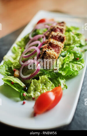 Salmone alla griglia rivestiti di sesamo con insalata di bulgur e verdure vista laterale Foto Stock