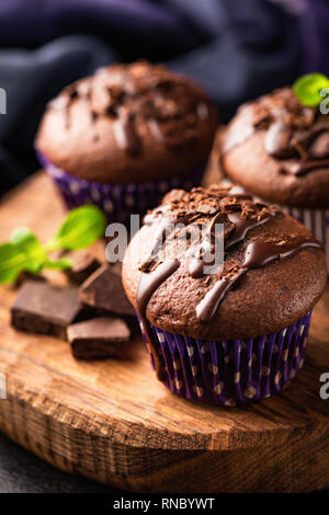 Torte al cioccolato decorato con cioccolato e foglia di menta su legno scheda servente. Primo piano. Gustoso cioccolato muffin o tortine Foto Stock