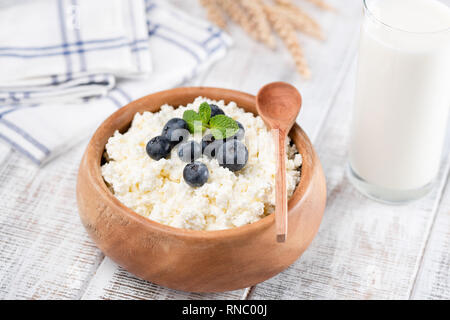 Tvorog o ricotta in ciotola di legno, bottiglia di latte di vacca e spighe di grano su tavola in legno rustico sfondo. Caseificio sano prodotti ricchi di proteina a Foto Stock