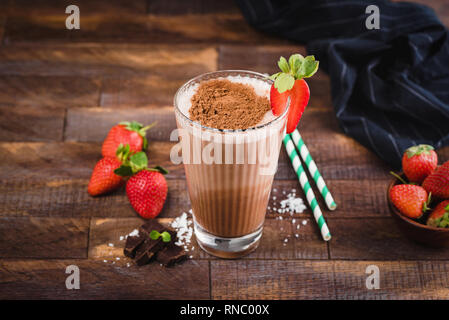 Frullato al cioccolato o un cocktail nel bicchiere di vetro marrone su sfondo di legno. Frullato di proteine con fragola Foto Stock