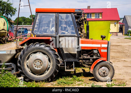 Vecchio trattore per opere in campi , dove coltivati a grano ed erba per le mucche . Vista laterale di una macchina agricola . Attrezzature per un caseificio. Foto Stock