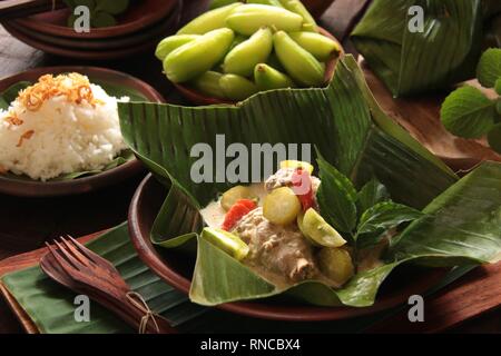 Garang Asem Ayam. Javanese tradizionale piatto di pungente pollo al curry in foglia di banano custodia. Foto Stock