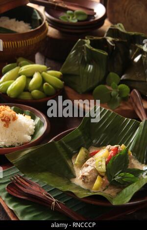 Garang Asem Ayam. Javanese tradizionale piatto di pungente pollo al curry in foglia di banano custodia. Foto Stock