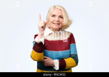 Emotivo nonna espressive puntando con il dito indice in alto Foto Stock
