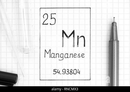Tavola periodica degli elementi. La grafia elemento chimico manganese Mn con la penna nera, tubo di prova e la pipetta. Close-up. Foto Stock