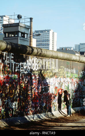 Un Occidente bambino tedesco tenta di chip off un pezzo del muro di Berlino come un souvenir. Una porzione della parete è già stata demolita a Potsdamer Platz. Foto Stock