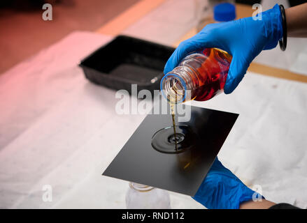 Fotografo riversa collodio soluzione sul nero sottile piastra di ferro. Piastra umida collodio processo. Foto Stock