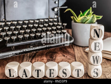 Parole Ultime notizie su blocchi di legno con la macchina da scrivere vintage e pianta in vaso in background Foto Stock