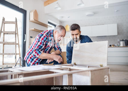 Un uomo maturo con il suo padre senior di assemblaggio di mobili, un nuovo concetto di casa. Foto Stock