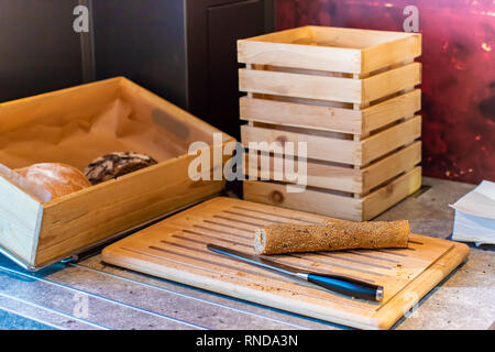 Pezzi di pane francese del baguette e il coltello su un tagliere di legno Foto Stock