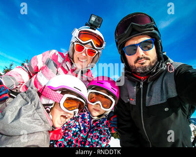 Famiglia godendo le vacanze invernali tenendo selfie in marcia di sci. Famiglia con bambini a sciare vacanza vestito di sci con ingranaggio di caschi da sci e gog Foto Stock