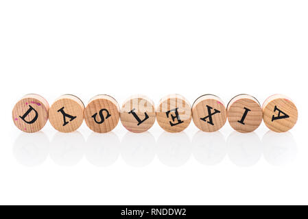 Parola dislessia da circolare piastrelle in legno con lettere giocattolo per bambini. Concetto di difficolta di apprendimento disturbo scritto nei bambini toy lettere. Foto Stock