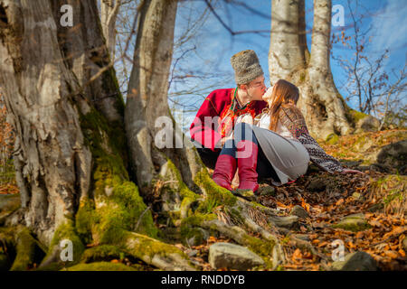 Giovane coppia felice, baci e amore, locale abiti tradizionali e giornata di sole nella foresta naturale europeo, uomo e donna Foto Stock