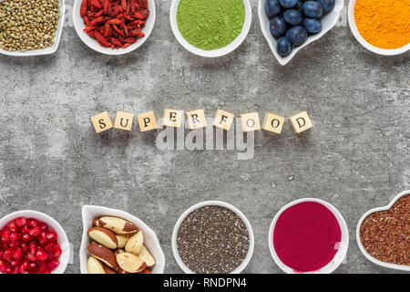 Super come acai polvere, curcuma, tè verde Matcha, zucca e semi di Chia, mirtillo bacche di goji, canapa e i semi di melograno sul calcestruzzo scuro bac Foto Stock