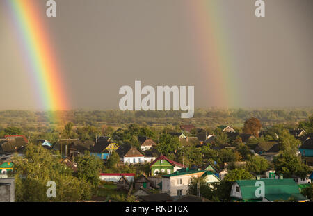 Arcobaleno doppio sopra la città, zona residenziale, doppio arcobaleno oltre il cielo blu, close-up Foto Stock