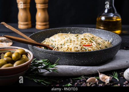 Pentola di cottura della pasta italiana. Tradizionale pasto di spaghetti con verdure e olive nere su sfondo rustico Foto Stock