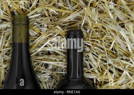 Composizione astratta di nero di due bottiglie di vino che giace sulla paglia Foto Stock