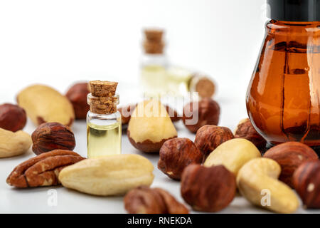 Dado di bottiglie di olio e varietà di dadi su bianco Foto Stock