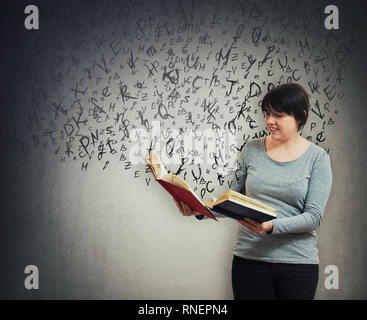 Donna studente o insegnante tiene due libri aperti e diverse lettere fuga dal libro di testo e battenti intorno a lei. Potenza della letteratura, istruzione e k Foto Stock