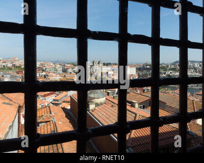 Un cielo blu roofscape vista del porto tetti da attraverso la vecchia prigione window grill bar finestra sbarrata Foto Stock