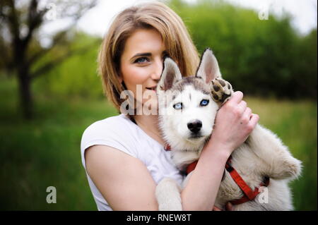 Una ragazza e il suo cane husky passeggiate nel parco Foto Stock