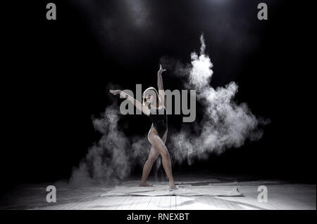 Ragazza ballare con una farina su sfondo nero. Foto Stock