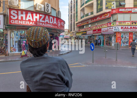 Close-up di un uomo pakistano visto da dietro in attesa in corrispondenza di un angolo di strada del e popolare quartiere di Deira in Dubai, United Arab Emirates, Foto Stock