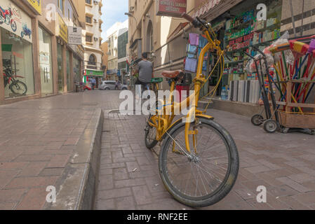 Vecchio e giallo bicicletta in piedi in mezzo alla strada nel popolare etnica e nel distretto di Deira di Dubai, Emirati Arabi Uniti. Foto Stock