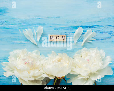 Bellissimi fiori e in legno lettere dell'alfabeto con parole di amore per la madre su uno sfondo blu. Vista superiore, close-up. Happy family concept Foto Stock
