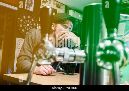 Bravo ragazzo irlandese di fumo di sigarette e di bere birra nei pub durante la St Patrick Day (filtro rappresentano bandiera irlandese) Foto Stock