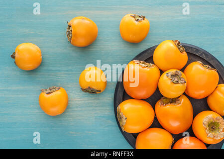 Vista dall'alto di orange mature cachi sulla piastra nera Foto Stock