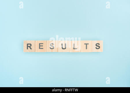 Vista superiore dei risultati di scritte fatte di cubi di legno su sfondo blu Foto Stock