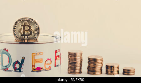 Salvataggio di bitcoins nella casella di denaro isolate su sfondo bianco e la pila di monete Foto Stock