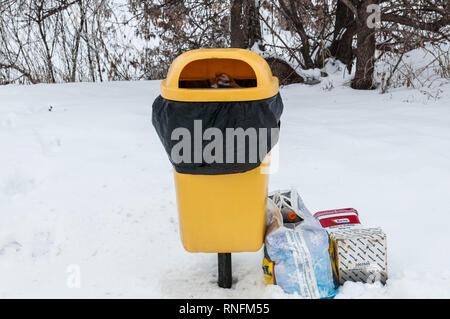 Una piena trashbin vicino a strade, sacchetti di plastica riempiti con cestino Foto Stock