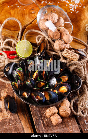 Bollito di cozze in piatto di rame per la cottura su sfondo in legno close-up Foto Stock