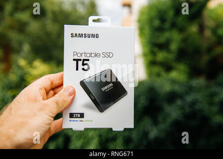 Parigi, Francia - 14 Ago, 2018: Man mano che tiene la nuova casella di Samsung T5 SSD portatile un disco rigido esterno ad alta velocità di lettura e scrittura contro lo sfondo di colore verde unboxing di testing Foto Stock