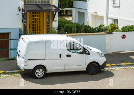Parigi, Francia - Agosto 10, 2018: Bianco Nissan furgone elettrico parcheggiato sulla strada distribuendo i pacchi da Logistica di Amazon - aprire il finestrino passeggero e un sacco di pacchi di cartoni all'interno Foto Stock