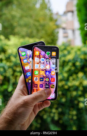 Parigi, Francia - Ott 2, 2018: orgoglioso uomo cliente POV confrontando il nuovo iPhone più recente e Xs Xs Max telefoni smartphone dopo l'unboxing contro verde all'aperto sullo sfondo della città Foto Stock