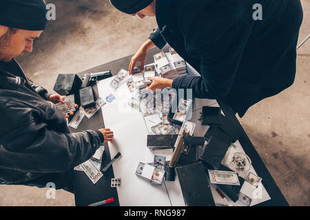 Ladri cercando soddisfatta tenendo denaro rubato Foto Stock