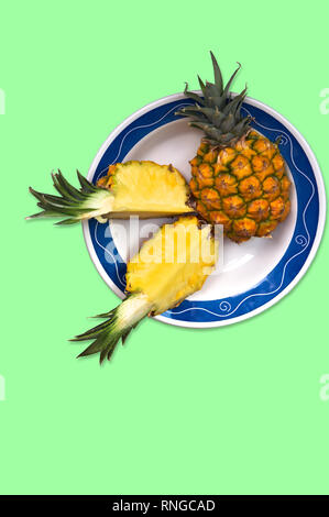 Vista dall'alto di un ananas maturo su una piastra blu con sfondo verde Foto Stock