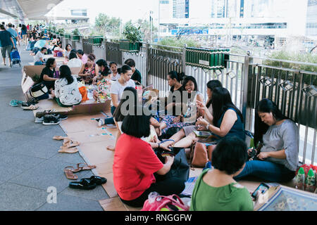 Filipiino lavoratori domestici sulla loro giornata di lavoro (domenica) raccogliere per divertimento e battute nelle strade di Honkong Foto Stock