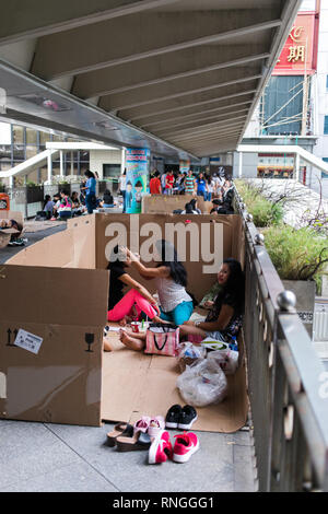 Filipiino lavoratori domestici sulla loro giornata di lavoro (domenica) raccogliere per divertimento e battute nelle strade di Honkong Foto Stock