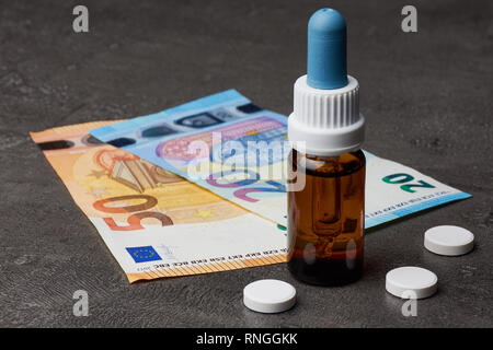 Bottiglia di medicina con compresse accanto a Euro Bills su sfondo scuro, Fotografia in verticale Foto Stock