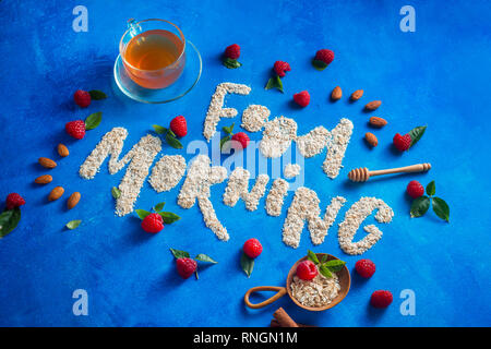 Buona mattina parole scritte con i fiocchi d'avena, lamponi e cannella. Mangiare sano concetto su una vibrante fresco di sfondo con copia spazio. Foto Stock