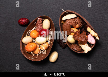 Vacanze concetto alimentare caramelle colorate e uova di pasqua di cioccolato nero sulla piastra di ardesia con spazio di copia Foto Stock